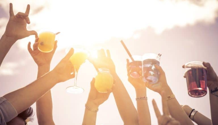 people holding up drink glasses in the sun