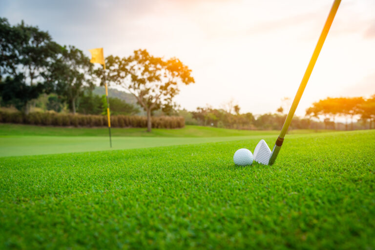 Golfer is putting golf ball on green grass at golf course for game with blur background and sunlight ray