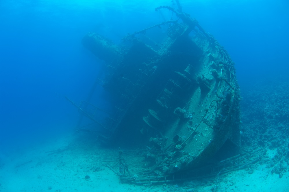 Stern section of a large underwater shipwreck on the seabed listing to port