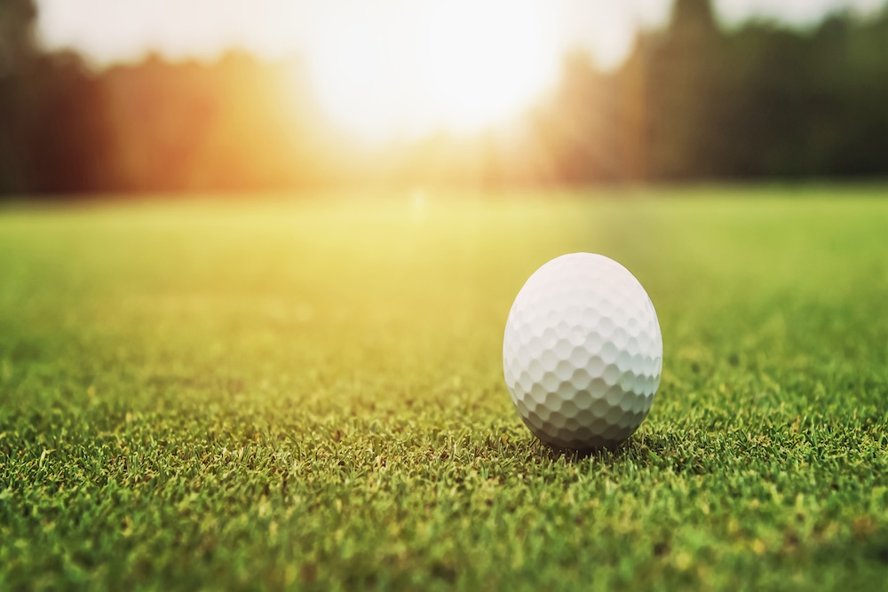 golf ball on green grass sunset background