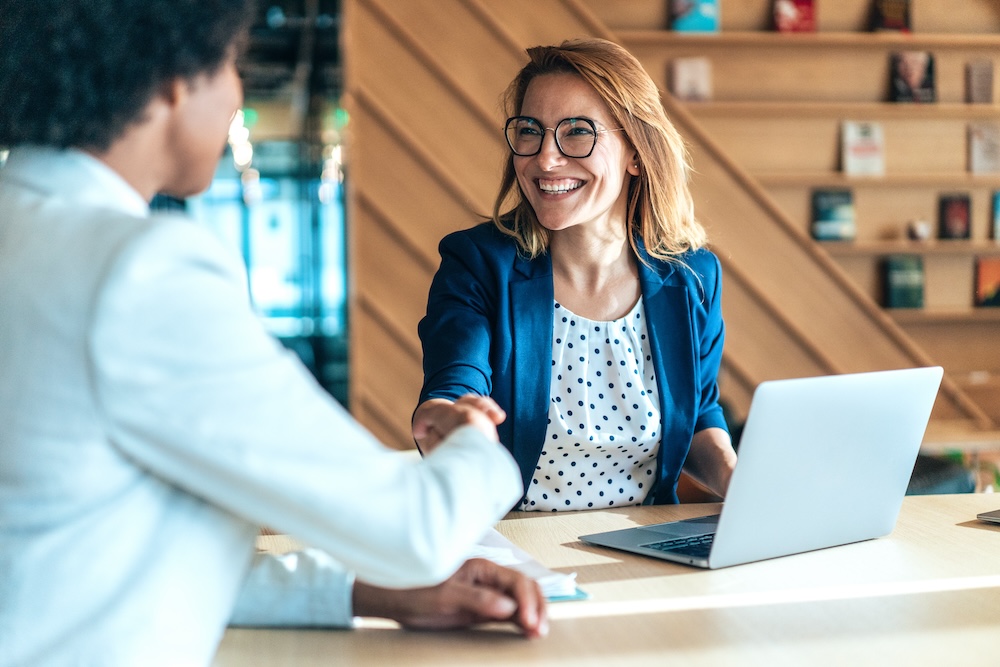 woman shaking hands with person in a business meeting