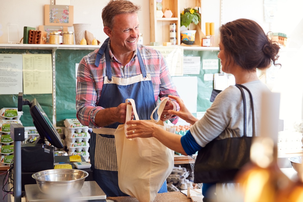Sales Assistant Serving Female Customer At Checkout Of Organic Farm Shop